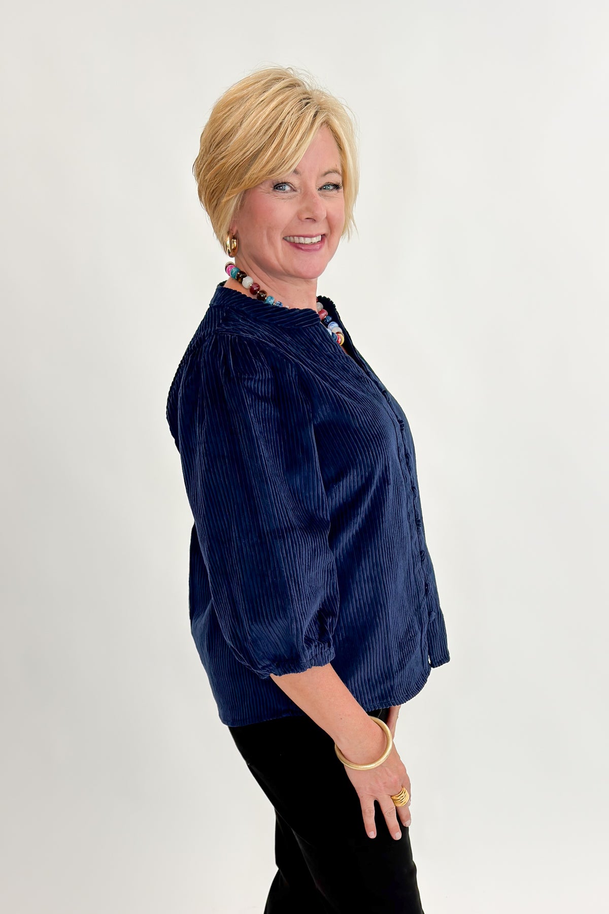 Side view of woman wearing Swagger Boutique’s Navy Corduroy Half Sleeve Top with jeans against white studio background.