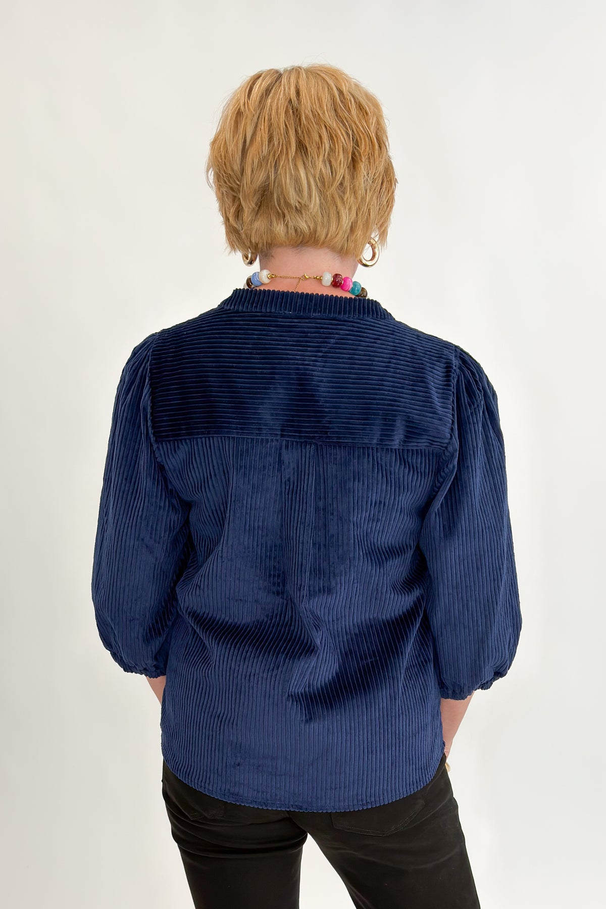 Back view of woman wearing Swagger Boutique’s Navy Corduroy Half Sleeve Top with jeans against white studio background.