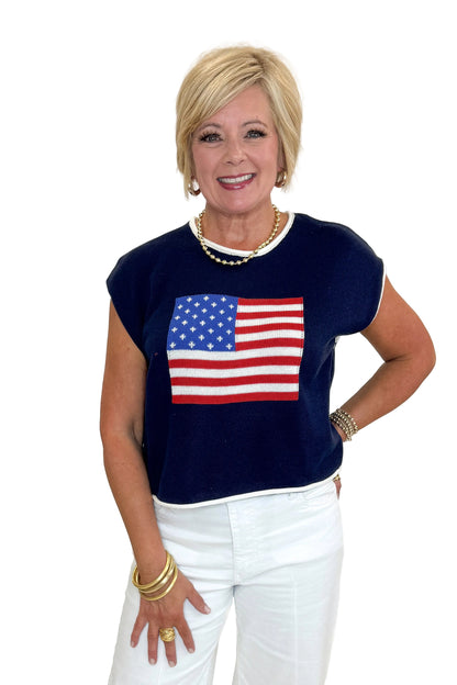Front view of woman wearing Swagger Boutique’s Right On Cue Navy Flag Short Sleeve Sweater with jeans against white studio background.