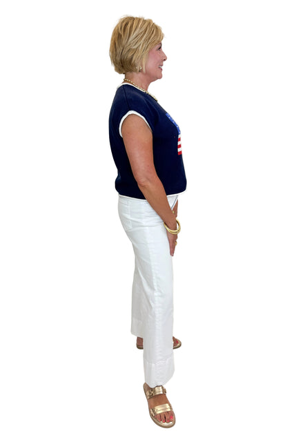 Side view of woman wearing Swagger Boutique’s Right On Cue Navy Flag Short Sleeve Sweater with jeans against white studio background.