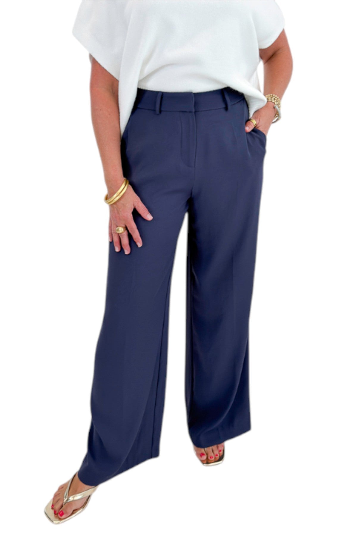 Front view of woman wearing Swagger Boutique’s Ivory Light Weight Short Sleeve Sweater with Navy High Waisted Trousers by Skies Are Blue against white studio background.