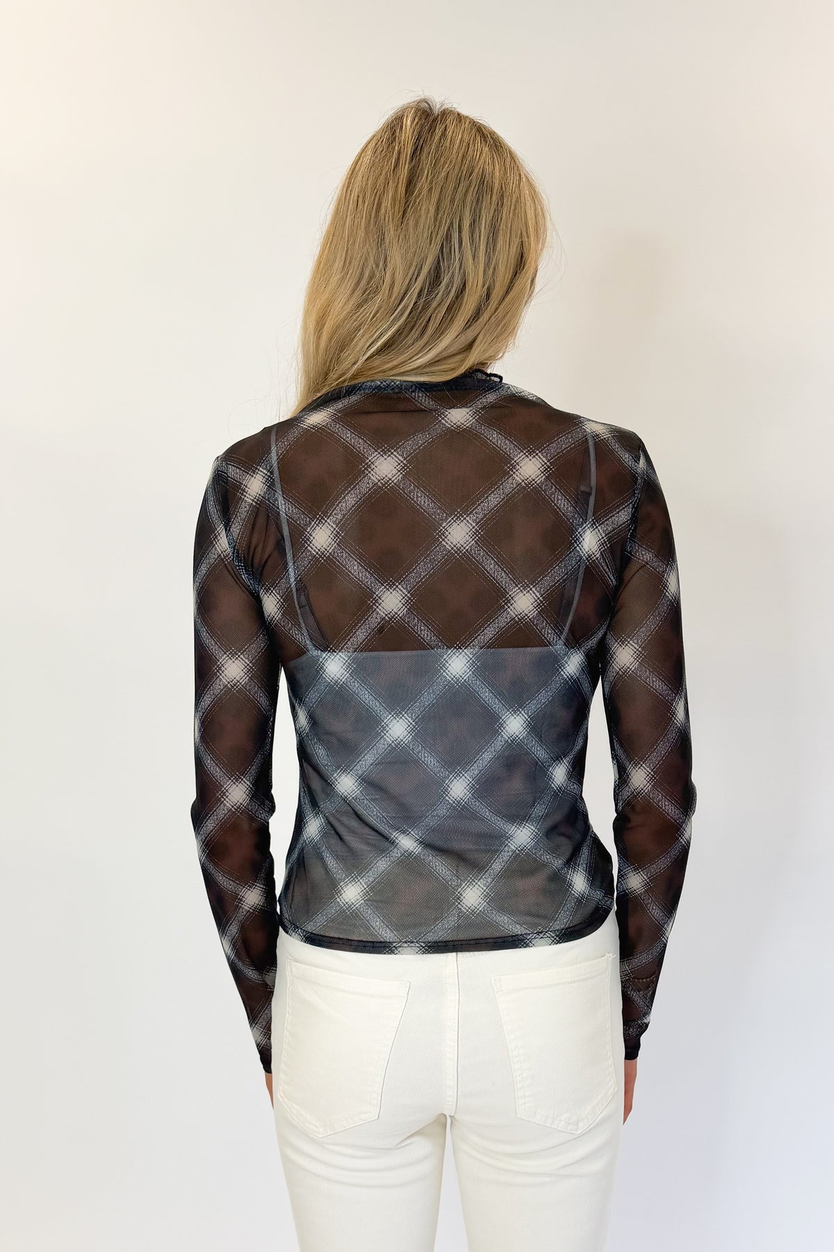 Back view of woman wearing Swagger Boutique’s Navy Plaid Mesh Top with jeans against white studio background.
