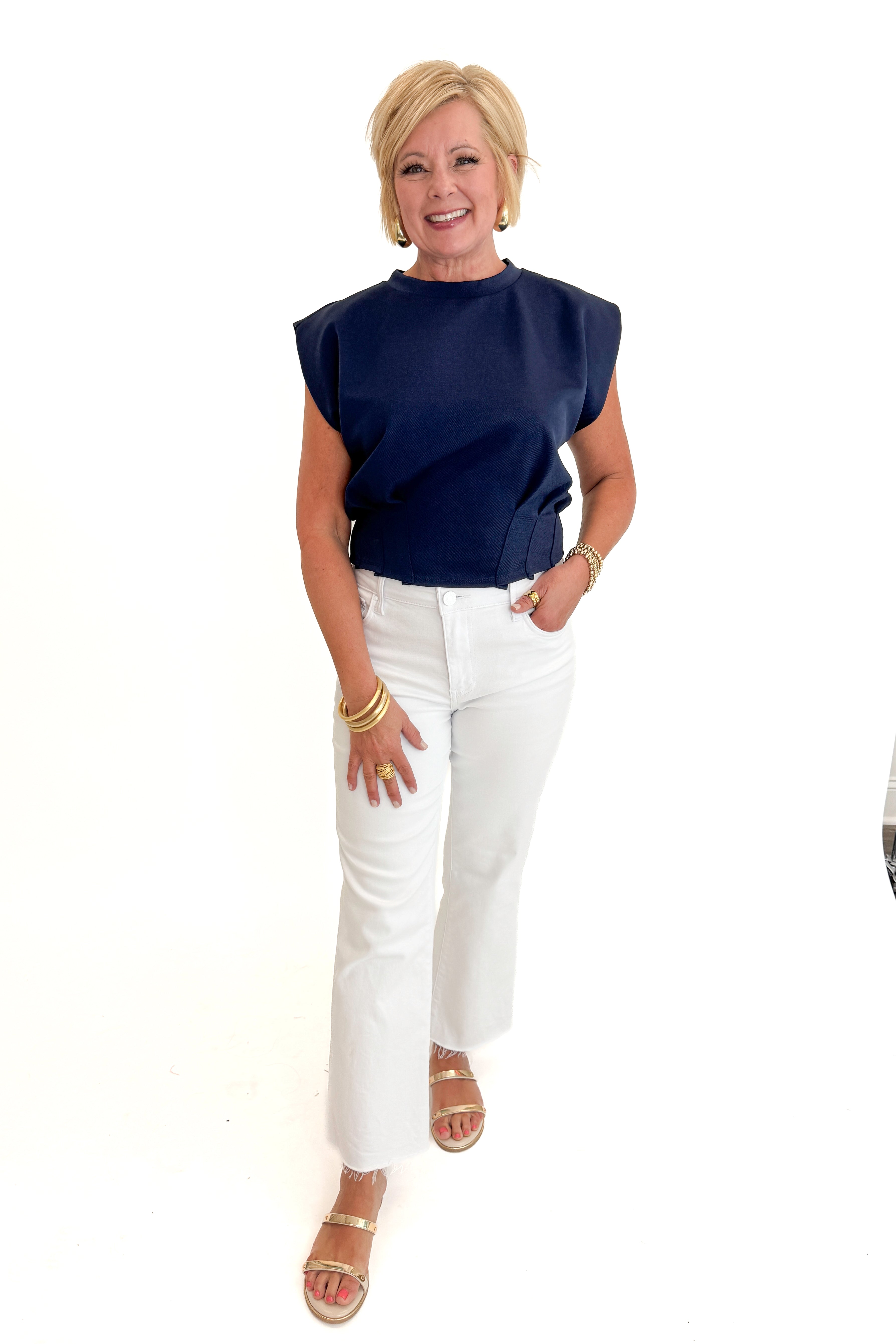 Front view of woman wearing Swagger Boutique’s Navy Pleat Detail Tank with jeans against white studio background.