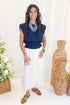 Front view of woman wearing Navy Pleat Detail Tank with skirt against decorative background.