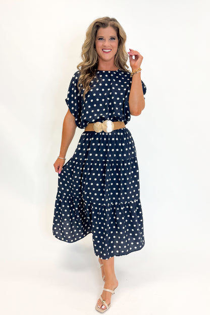 Front view of woman wearing Swagger Boutique’s Navy Polka Dot Bubble Hem Top by Entro with matching Navy Polka Dot Tiered Skirt by Entro against white studio background.