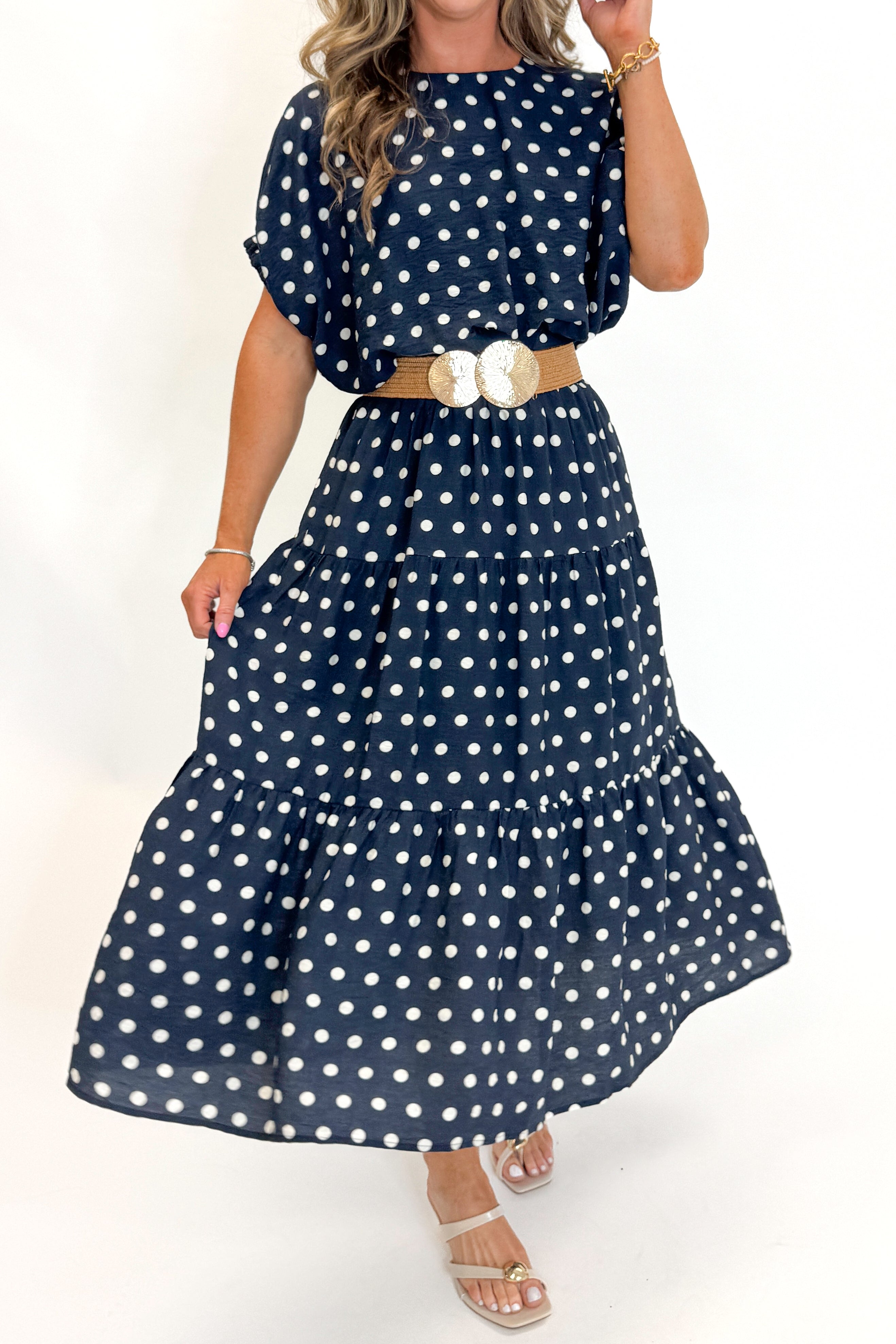 Side detail view of woman wearing Swagger Boutique’s Navy Polka Dot Bubble Hem Top by Entro with matching Navy Polka Dot Tiered Skirt by Entro against white studio background.
