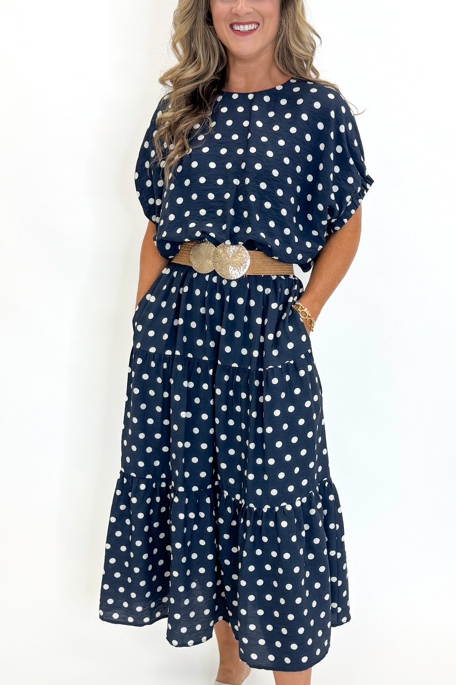 Front view of woman wearing Swagger Boutique’s Navy Polka Dot Bubble Hem Top by Entro with matching Navy Polka Dot Tiered Skirt by Entro against white studio background.