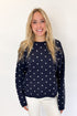 Front view of woman wearing Swagger Boutique’s Navy Polka Dot Sweater with jeans against white studio background.