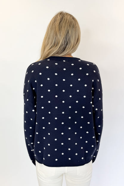 Back view of woman wearing Swagger Boutique’s Navy Polka Dot Sweater with jeans against white studio background.