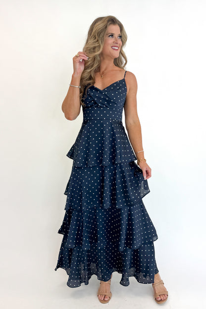 Front view of woman wearing Swagger Boutique’s Navy Polka Dot Tiered Maxi Dress against white studio background.