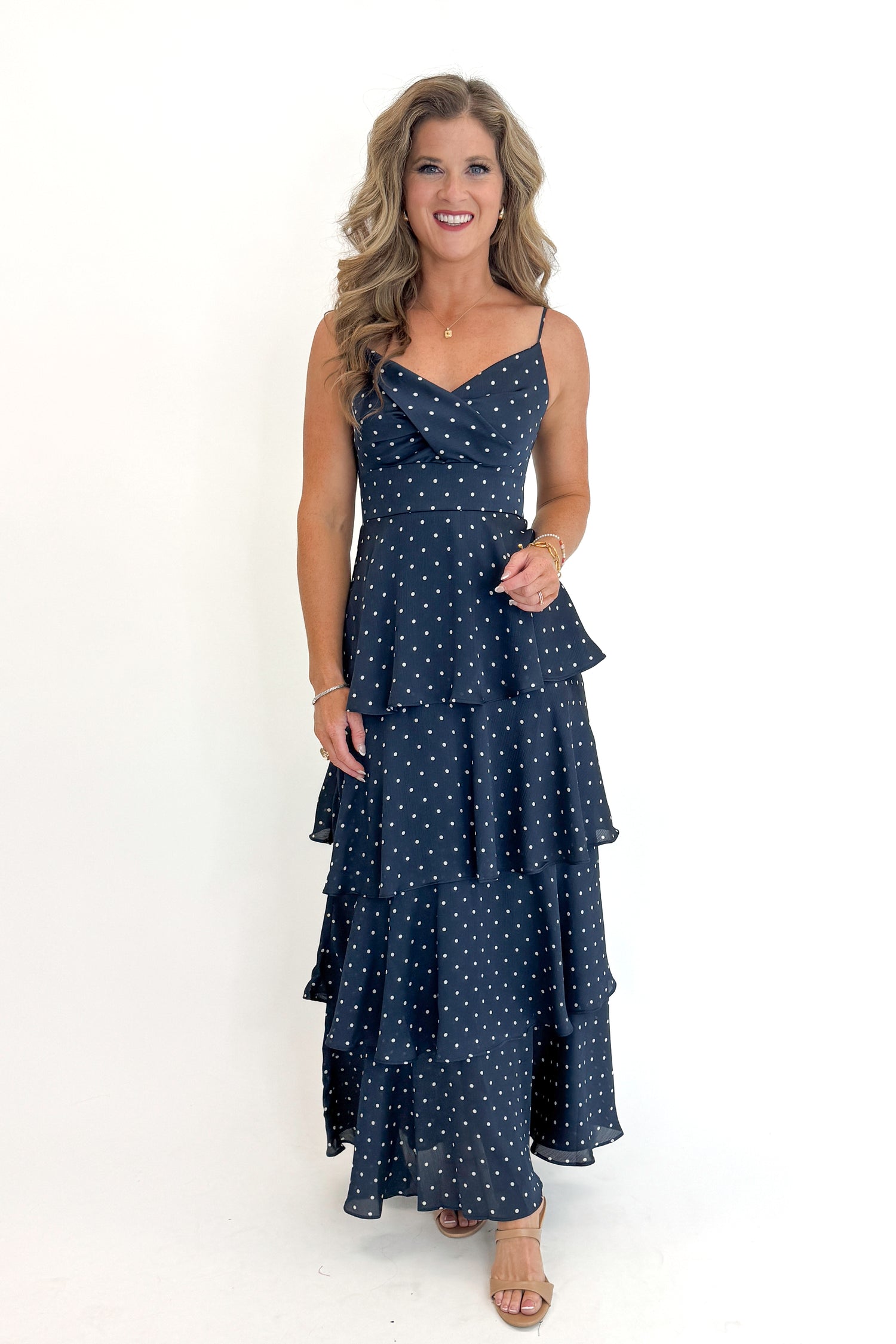 Front view of woman wearing Swagger Boutique’s Navy Polka Dot Tiered Maxi Dress against white studio background.
