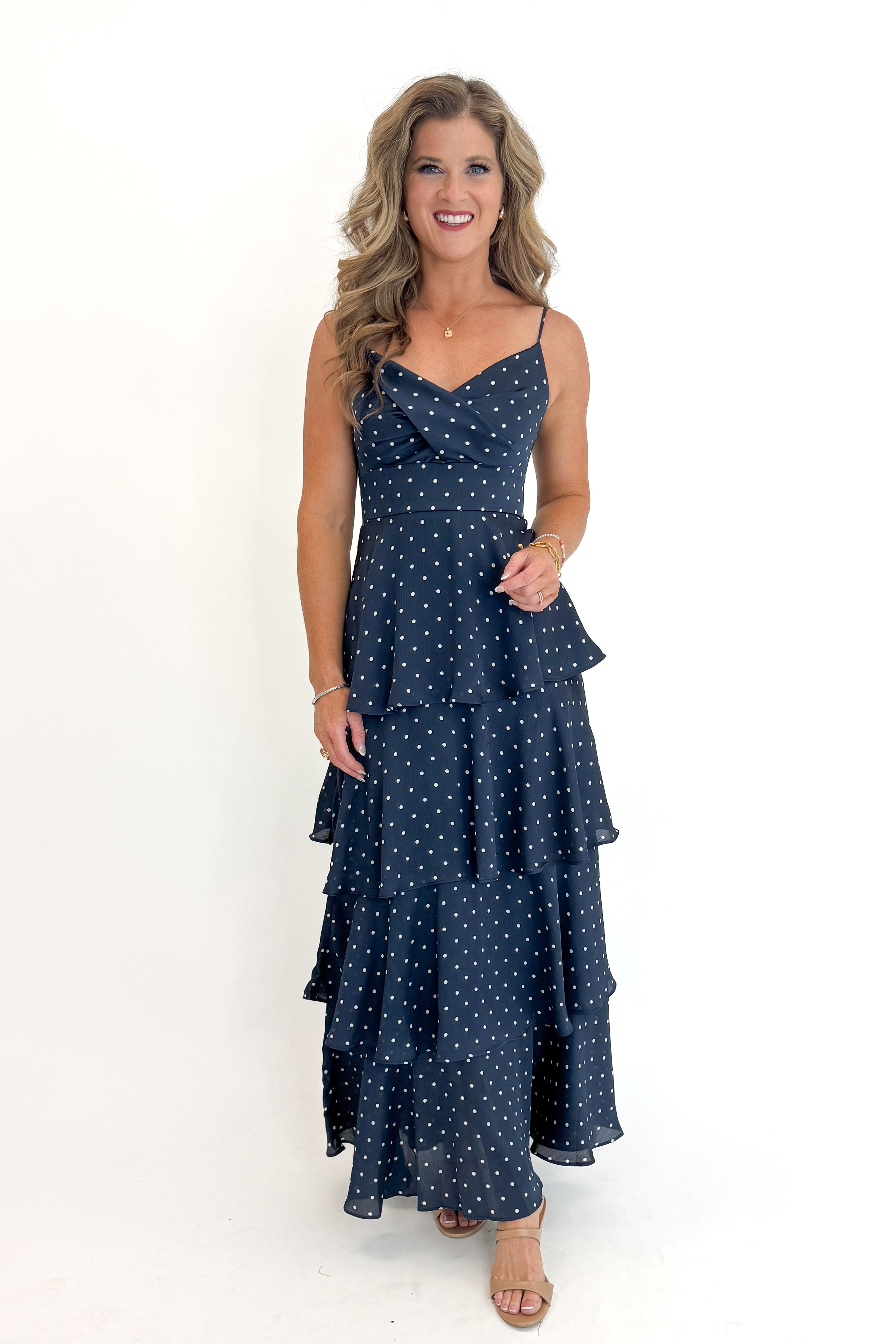 Front view of woman wearing Swagger Boutique’s Navy Polka Dot Tiered Maxi Dress against white studio background.