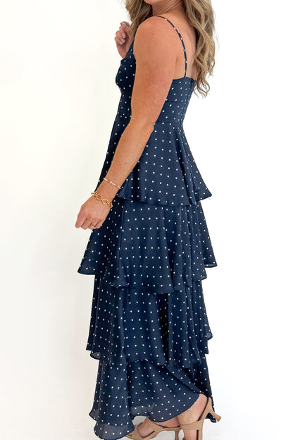 Side detail view of woman wearing Swagger Boutique’s Navy Polka Dot Tiered Maxi Dress against white studio background.