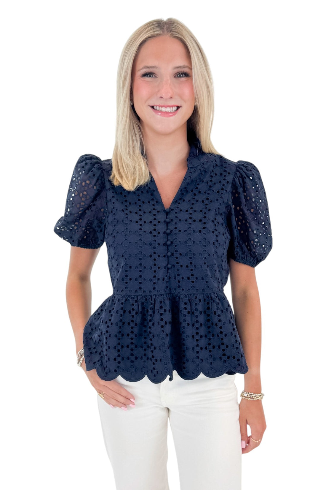 Front view of woman wearing Navy Short Sleeve Peplum Eyelet Top with jeans against white studio background.