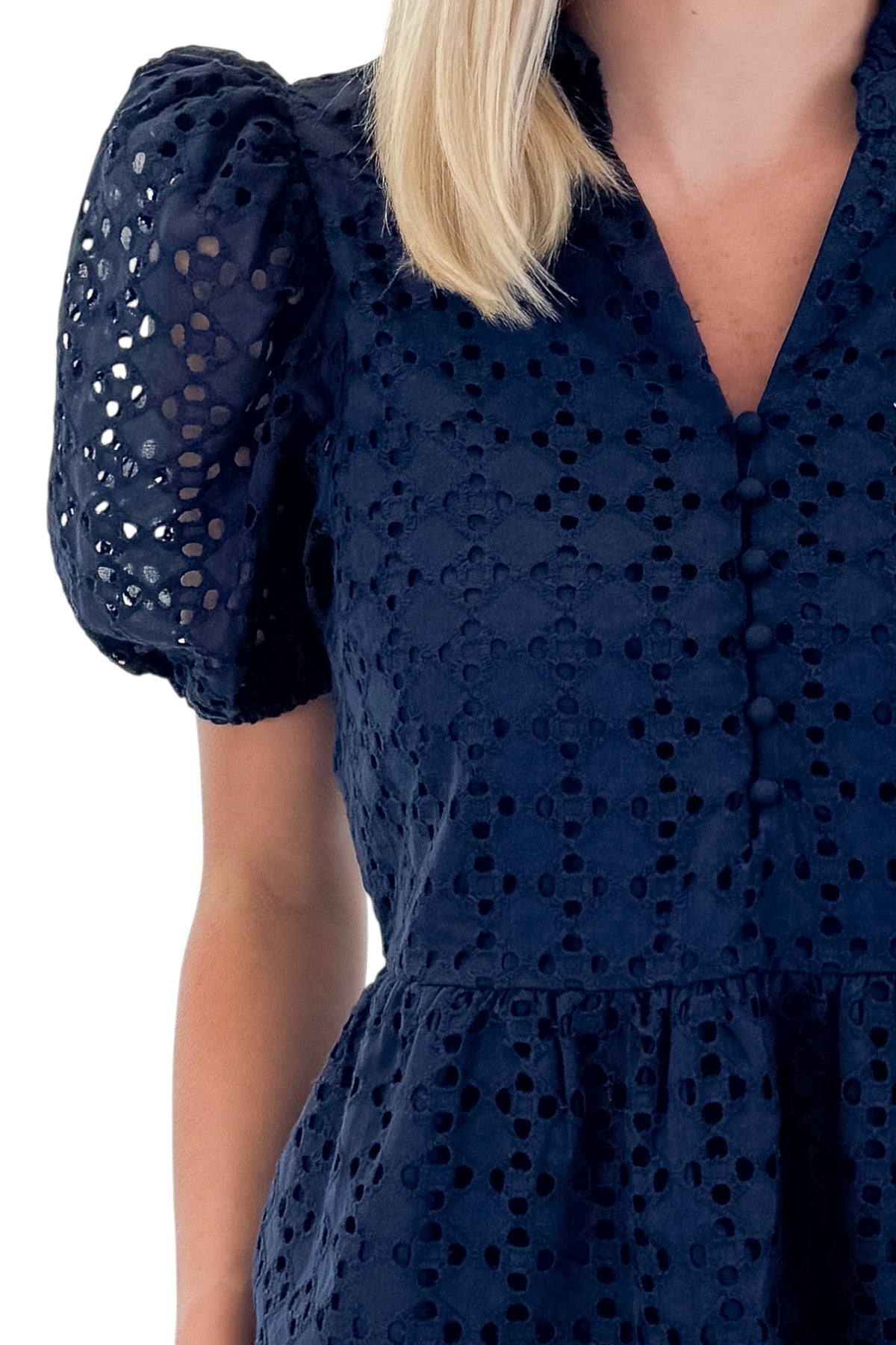Front detail view of woman wearing Navy Short Sleeve Peplum Eyelet Top with jeans against white studio background.