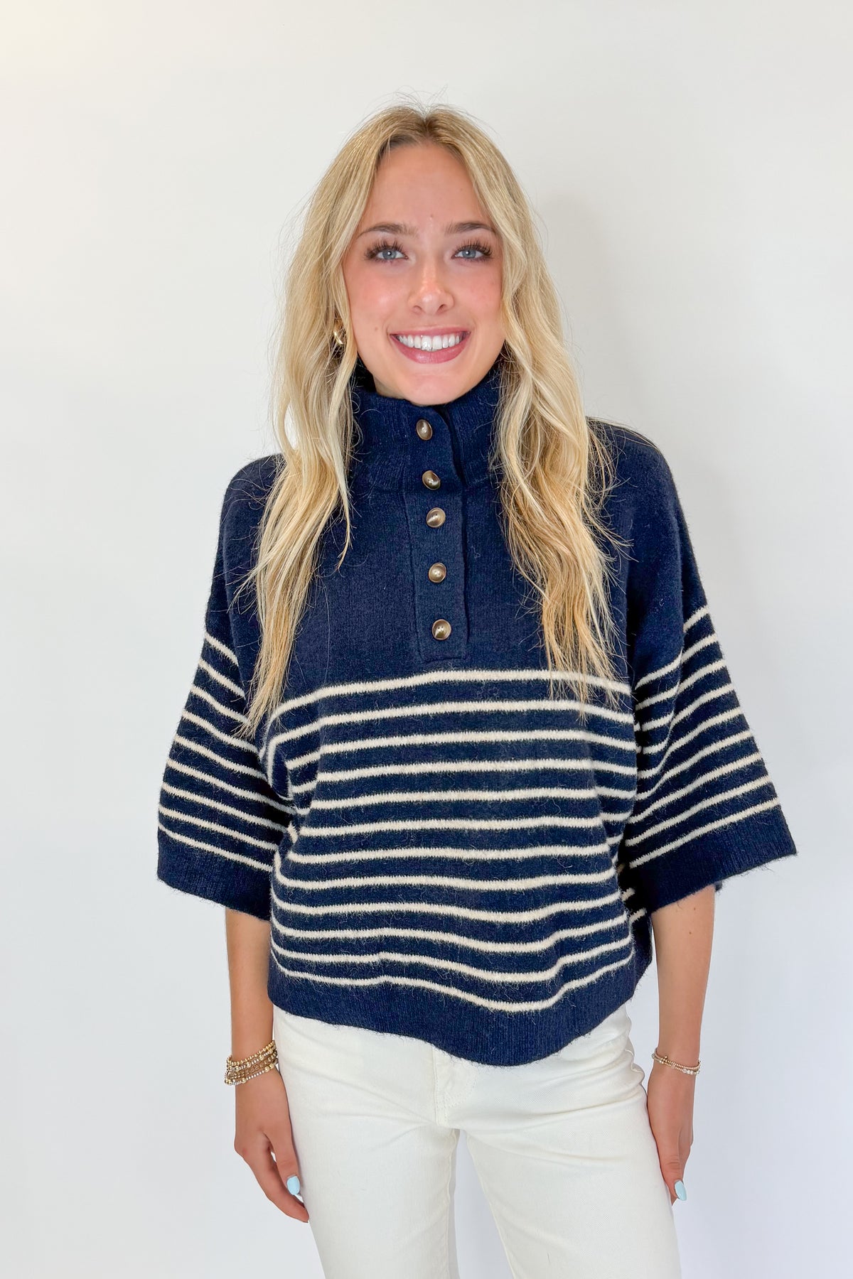 Front view of woman wearing Swagger Boutique’s Navy Striped 3/4 Sleeve Sweater by Entro with jeans against white studio background.