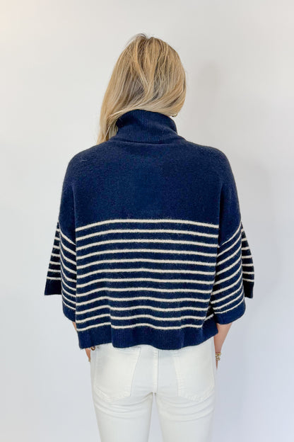 Back view of woman wearing Swagger Boutique’s Navy Striped 3/4 Sleeve Sweater by Entro with jeans against white studio background.