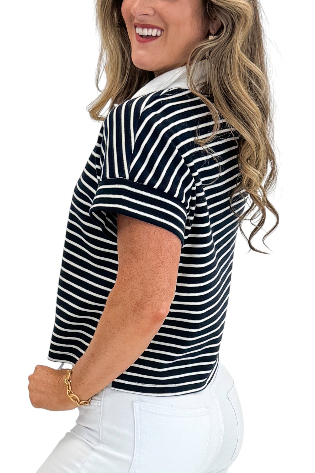 Side detail view of woman wearing Swagger Boutique’s Navy Striped Collared Top by Entro with jeans against white studio background.