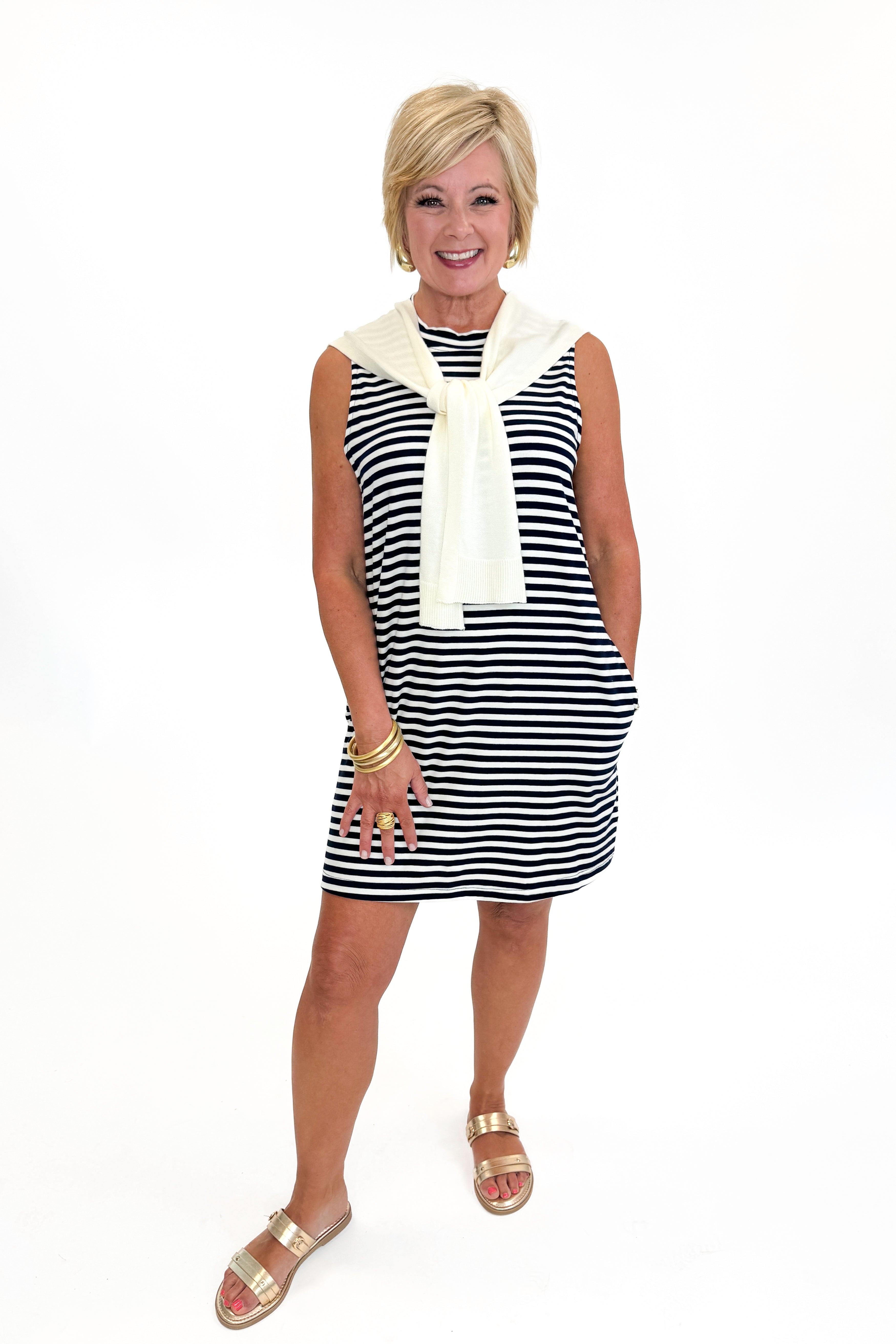 Front view of woman wearing Swagger Boutique’s Navy Striped Faux Layered Mini Dress with sandals against white studio background.