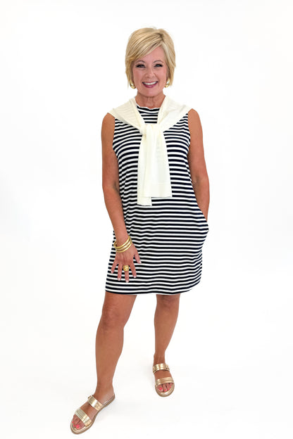 Front view of woman wearing Swagger Boutique’s Navy Striped Faux Layered Mini Dress with sandals against white studio background.