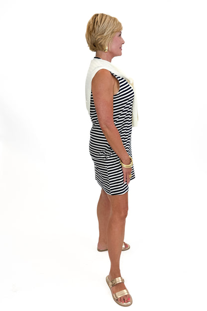 Side view of woman wearing Swagger Boutique’s Navy Striped Faux Layered Mini Dress with sandals against white studio background.