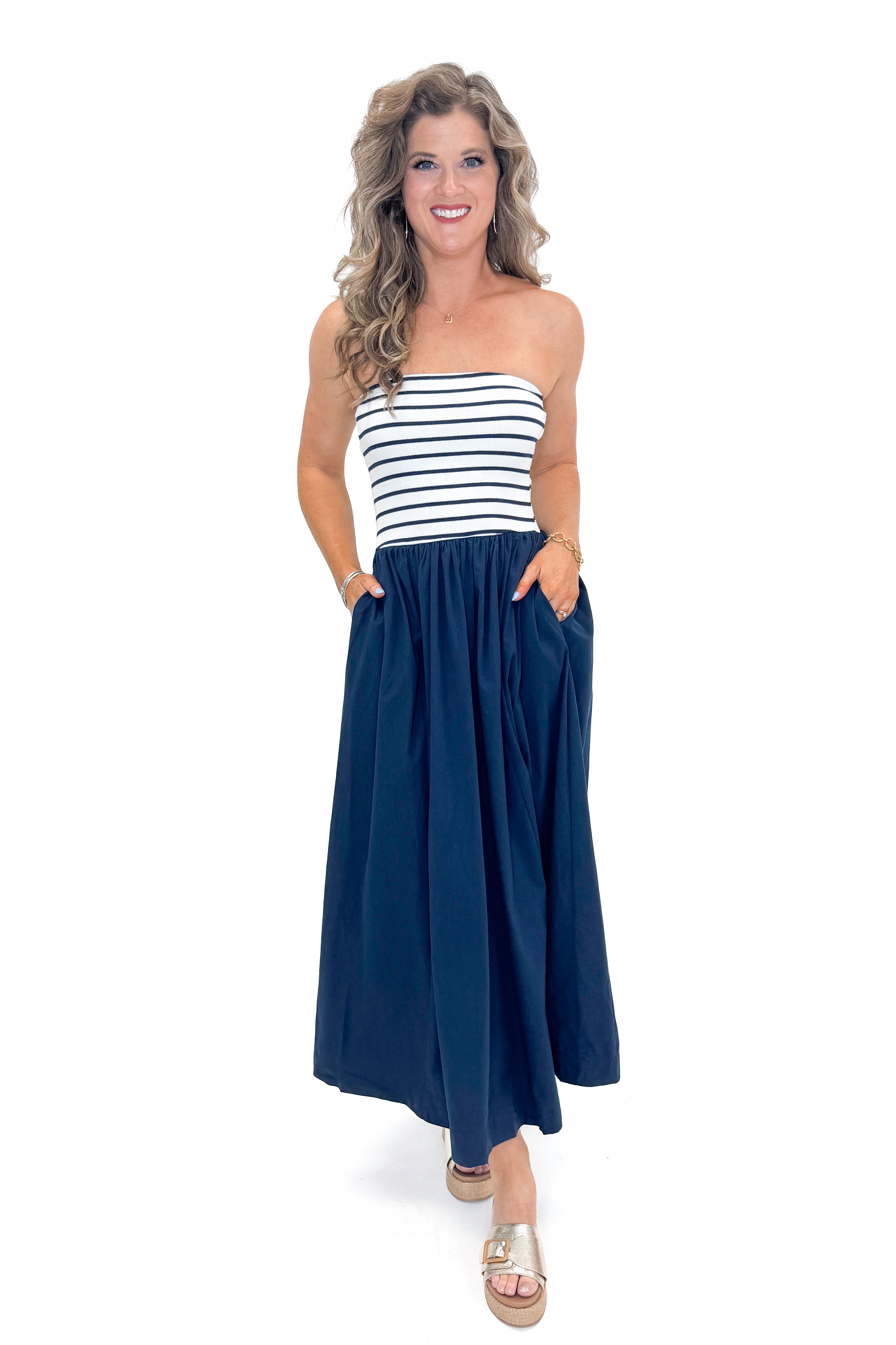 Front view of woman wearing Swagger Boutique’s Navy Striped Maxi Dress with sandals against white studio background.