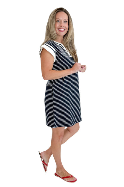 Side view of woman wearing Swagger Boutique’s Navy Striped V-Neck Shift Dress with sandals against white studio background.
