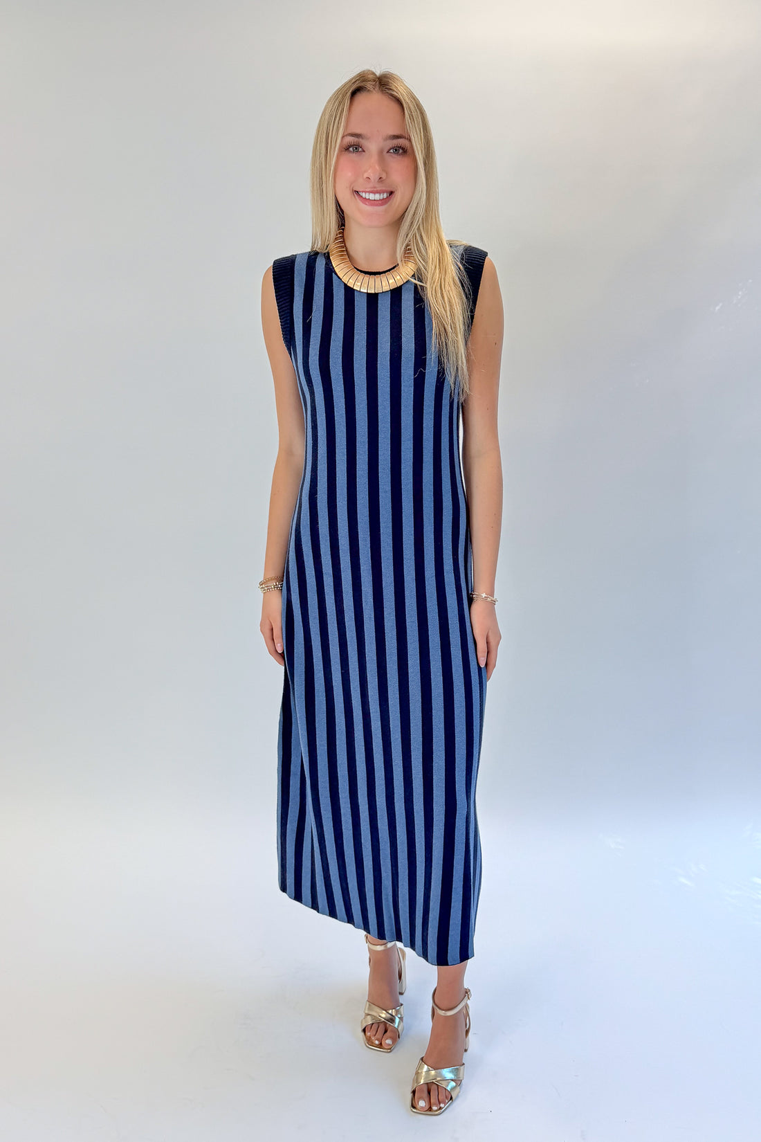 Front view of woman wearing Swagger Boutique’s Navy &amp; Blue Striped Midi Dress with heels against white studio background.