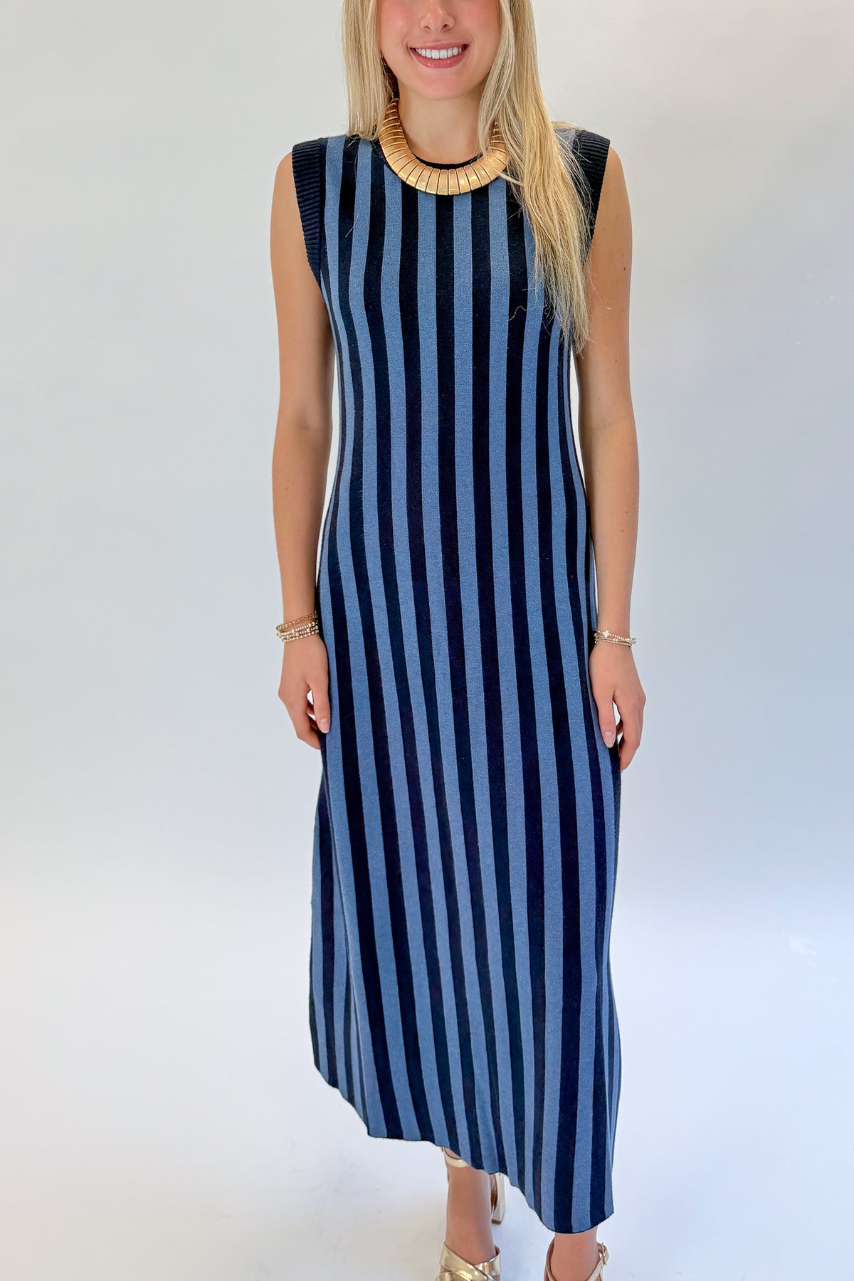 Front detail view of woman wearing Swagger Boutique’s Navy &amp; Blue Striped Midi Dress with heels against white studio background.