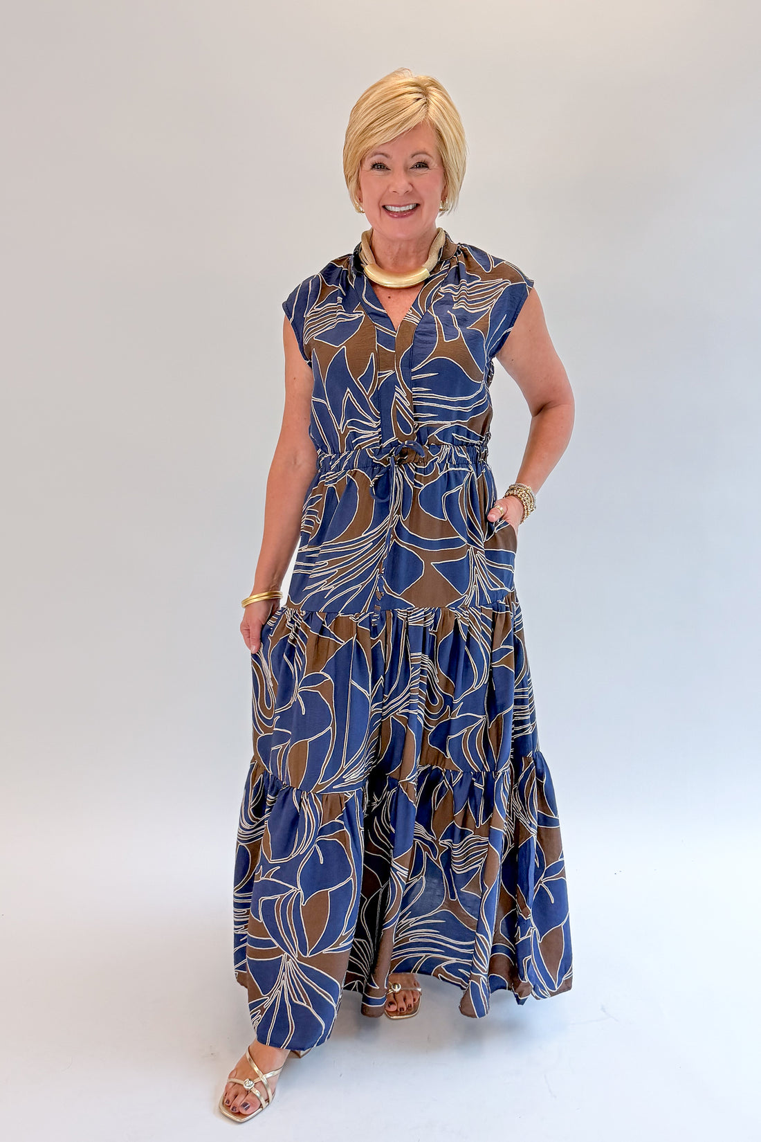 Front view of woman wearing Swagger Boutique’s Navy &amp; Brown Abstract Print Maxi Dress with heels against white studio background.