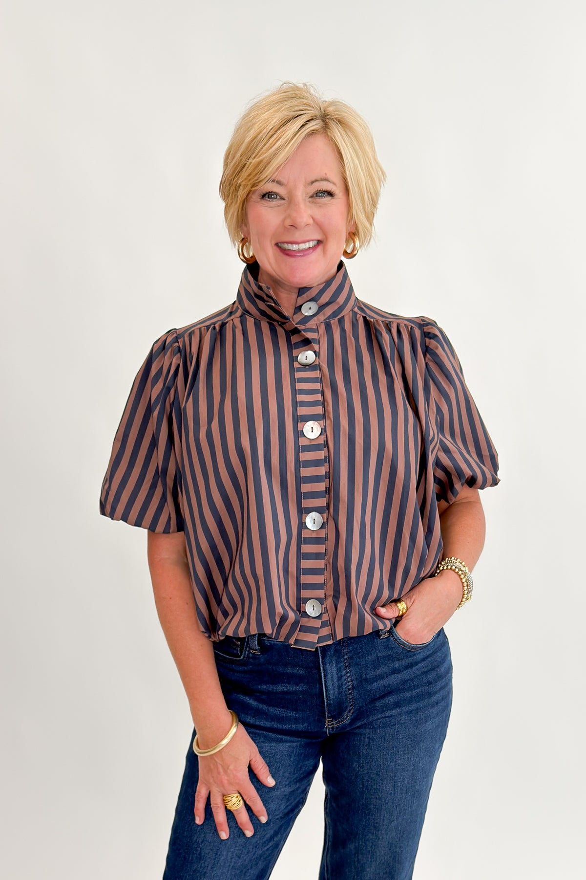 Front view of woman wearing Swagger Boutique’s Navy &amp; Brown Striped Bubble Hem Top with jeans against white studio background.