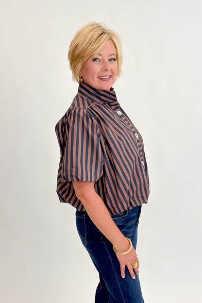 Side view of woman wearing Swagger Boutique’s Navy &amp; Brown Striped Bubble Hem Top with jeans against white studio background.