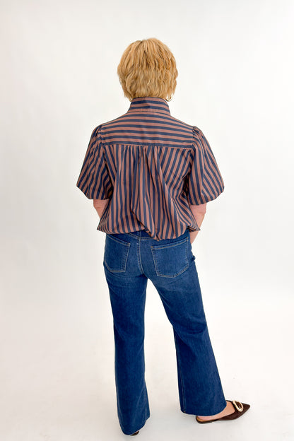 Back view of woman wearing Swagger Boutique’s Navy &amp; Brown Striped Bubble Hem Top with jeans against white studio background.