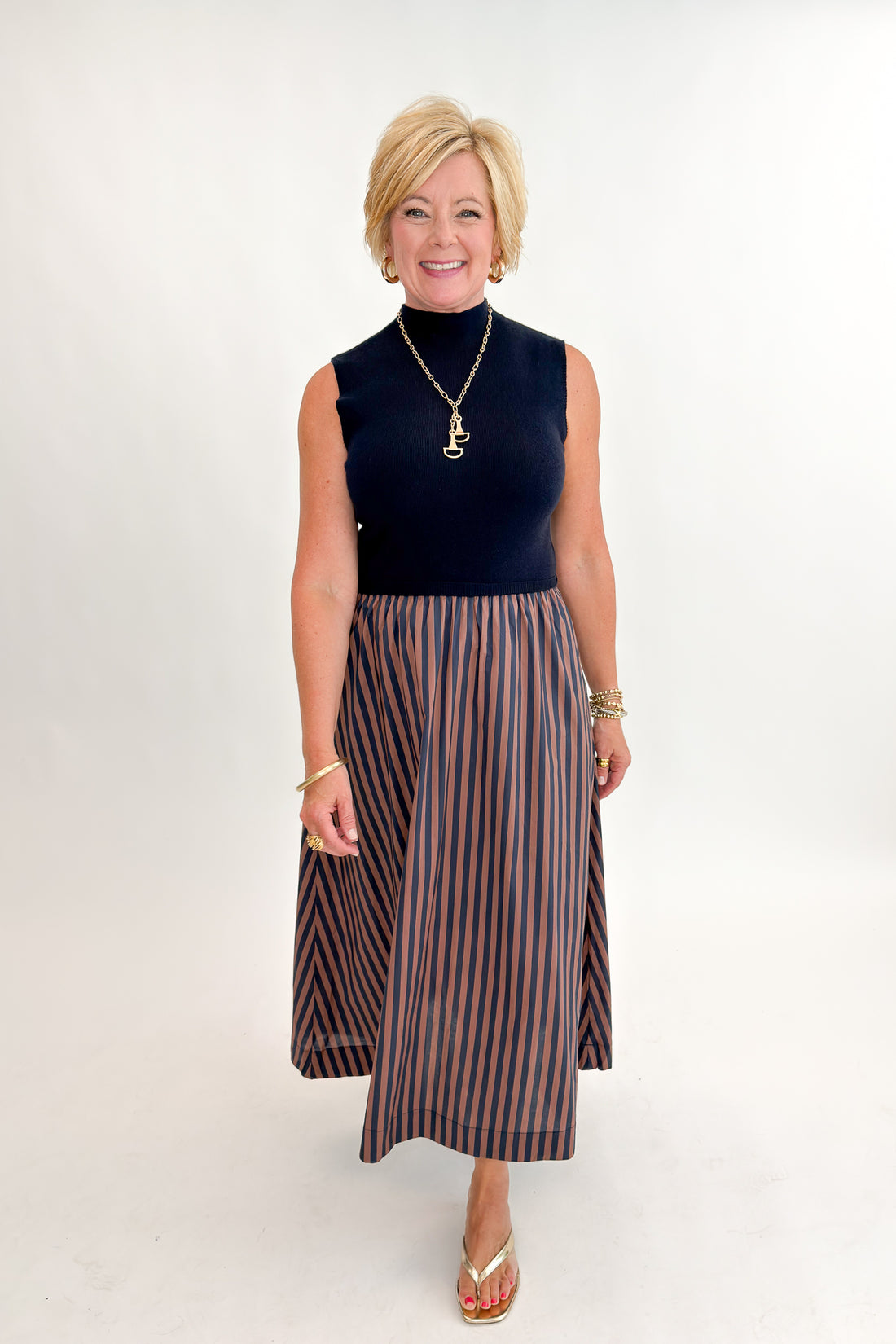 Front view of woman wearing Swagger Boutique’s Navy &amp; Brown Striped Layered Mock Neck Midi Dress against white studio background.