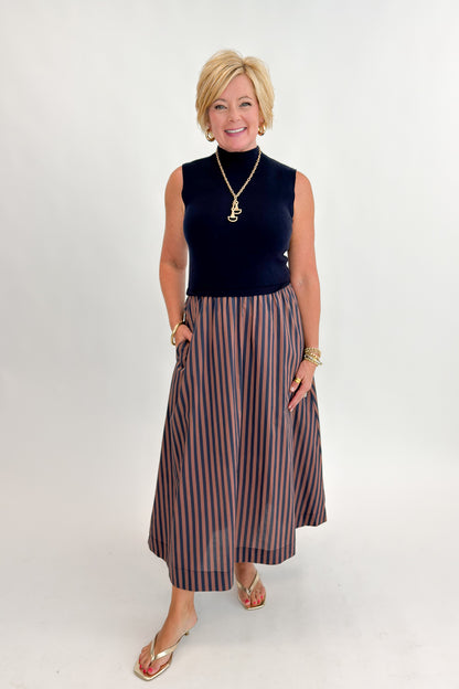 Front view of woman wearing Swagger Boutique’s Navy &amp; Brown Striped Layered Mock Neck Midi Dress against white studio background.