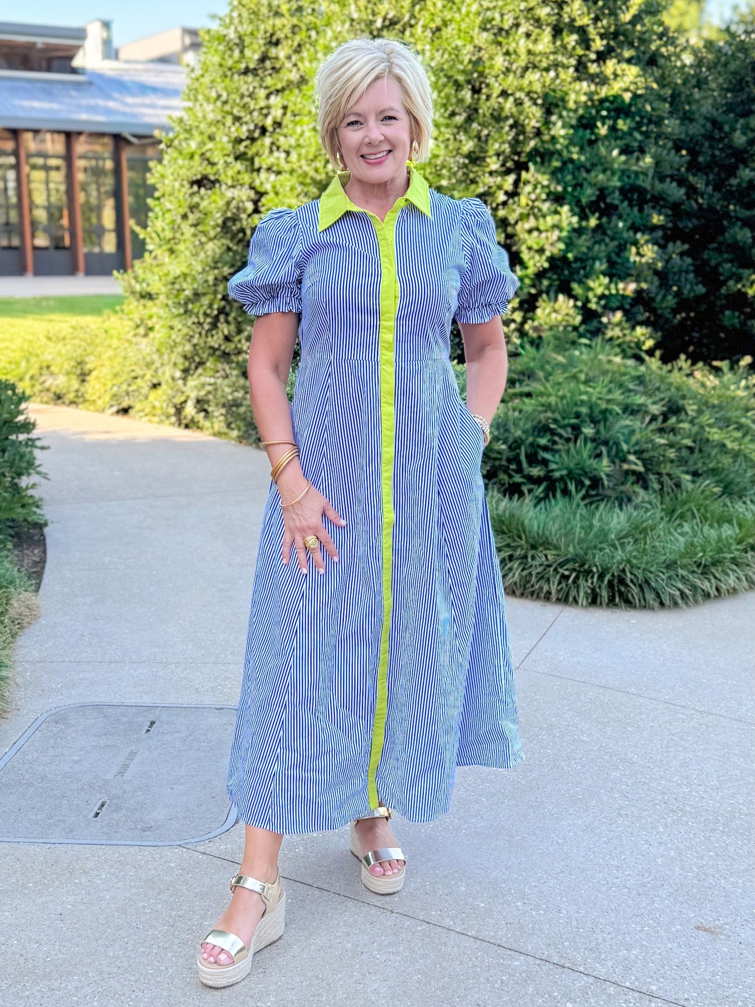 Front view of woman wearing Swagger Boutique’s Navy &amp; Citron Striped Midi Dress by Entro with sandals standing outside at a park.
