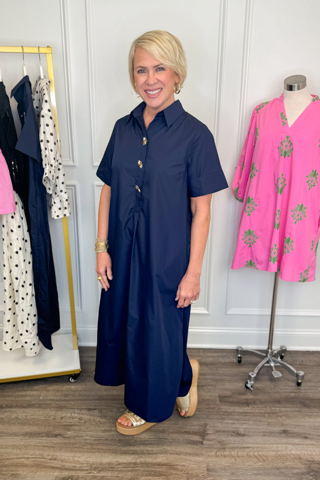Side view of woman wearing Swagger Boutique’s Navy Collared Midi Dress by Entro with platform sandals with clothes near her. 