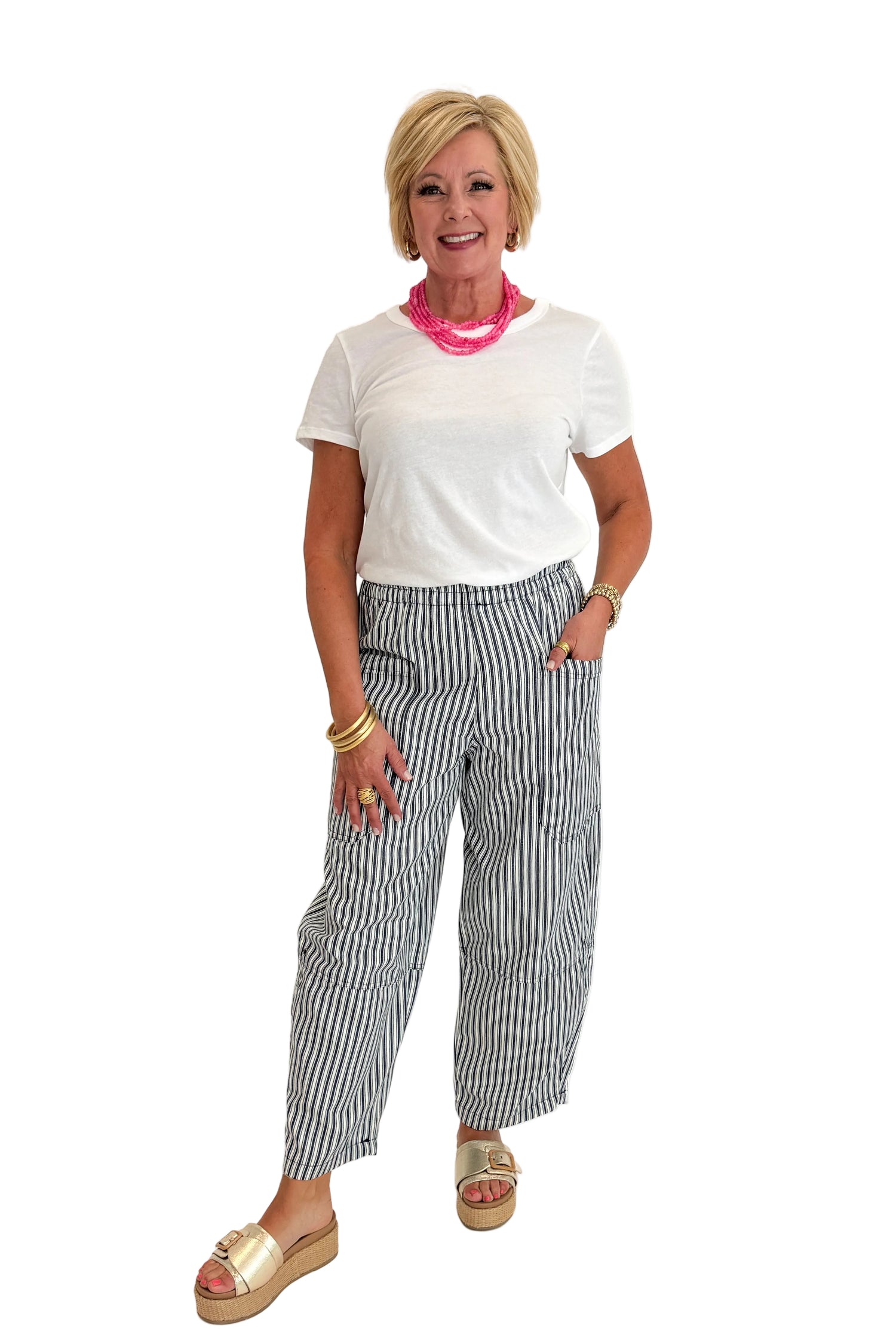 Front view of woman wearing Swagger Boutique’s In Full Swing Navy &amp; Cream Striped Barrel Pants with white top and sandals against white studio background.