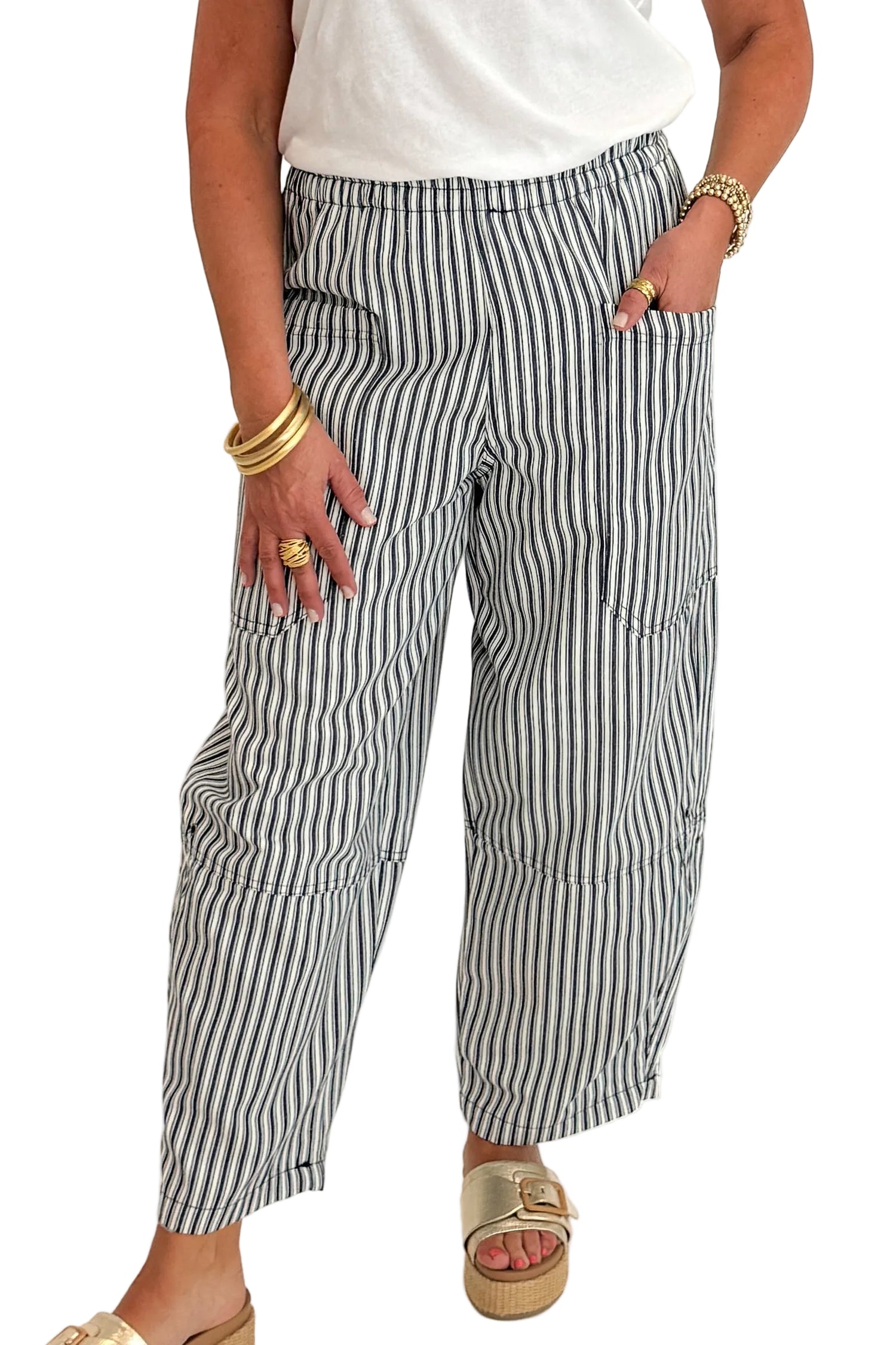Front detail view of woman wearing Swagger Boutique’s In Full Swing Navy &amp; Cream Striped Barrel Pants with white top and sandals against white studio background.