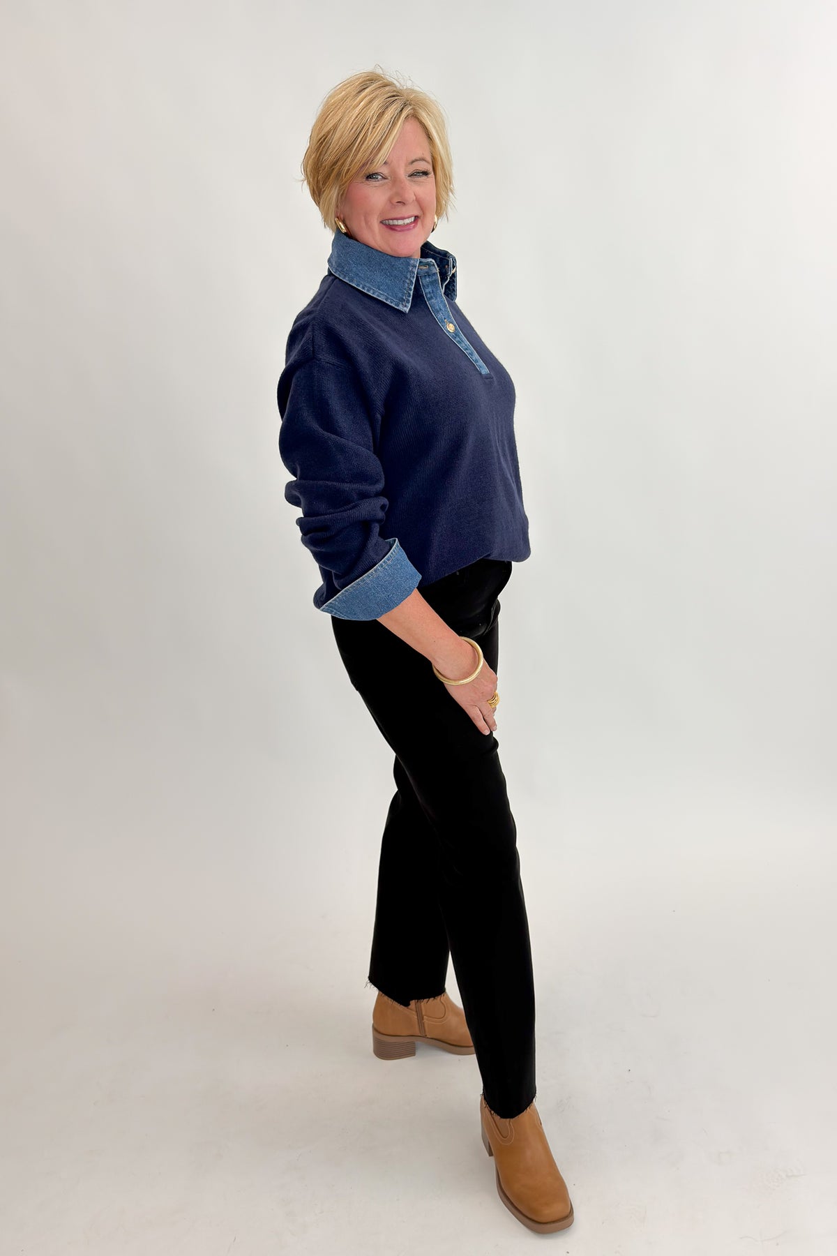 Side view of woman wearing Swagger Boutique’s Navy &amp; Denim Collared Sweater with jeans against white studio background.