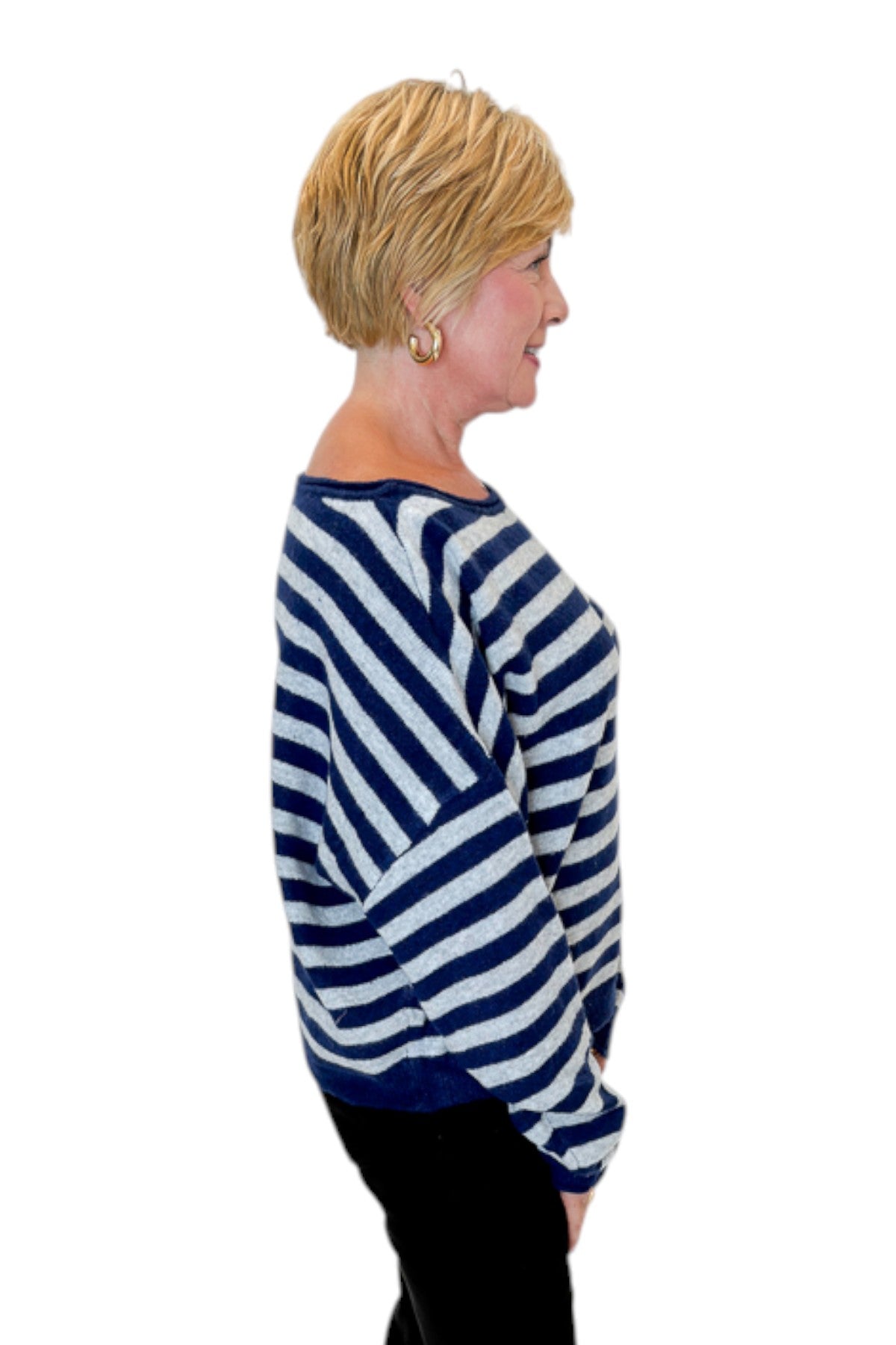 Side view of woman wearing Swagger Boutique’s Navy &amp; Grey Striped Sweater with jeans against white studio background.