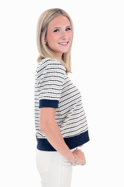 Side view of woman wearing Swagger Boutique’s Navy &amp; Light Blue Striped Short Sleeve Top by Entro with jeans against white studio background.