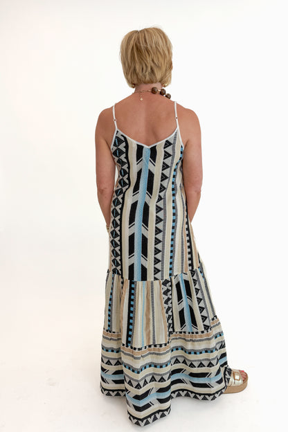 Back view of woman wearing Swagger Boutique’s Neutral Aztec Print Maxi Dress with sandals against white studio background.