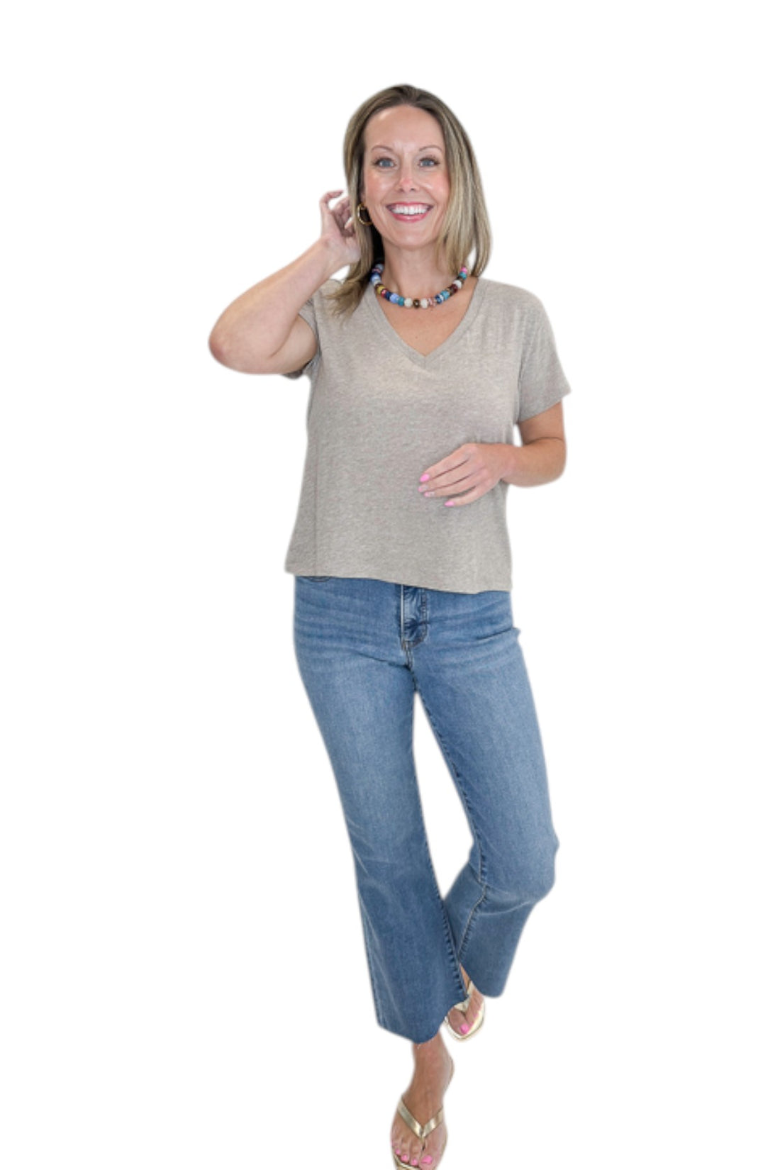 Front view of woman wearing Swagger Boutique’s Heather Ash Nomad V-Neck Tee by Z Supply with jeans against white studio background.