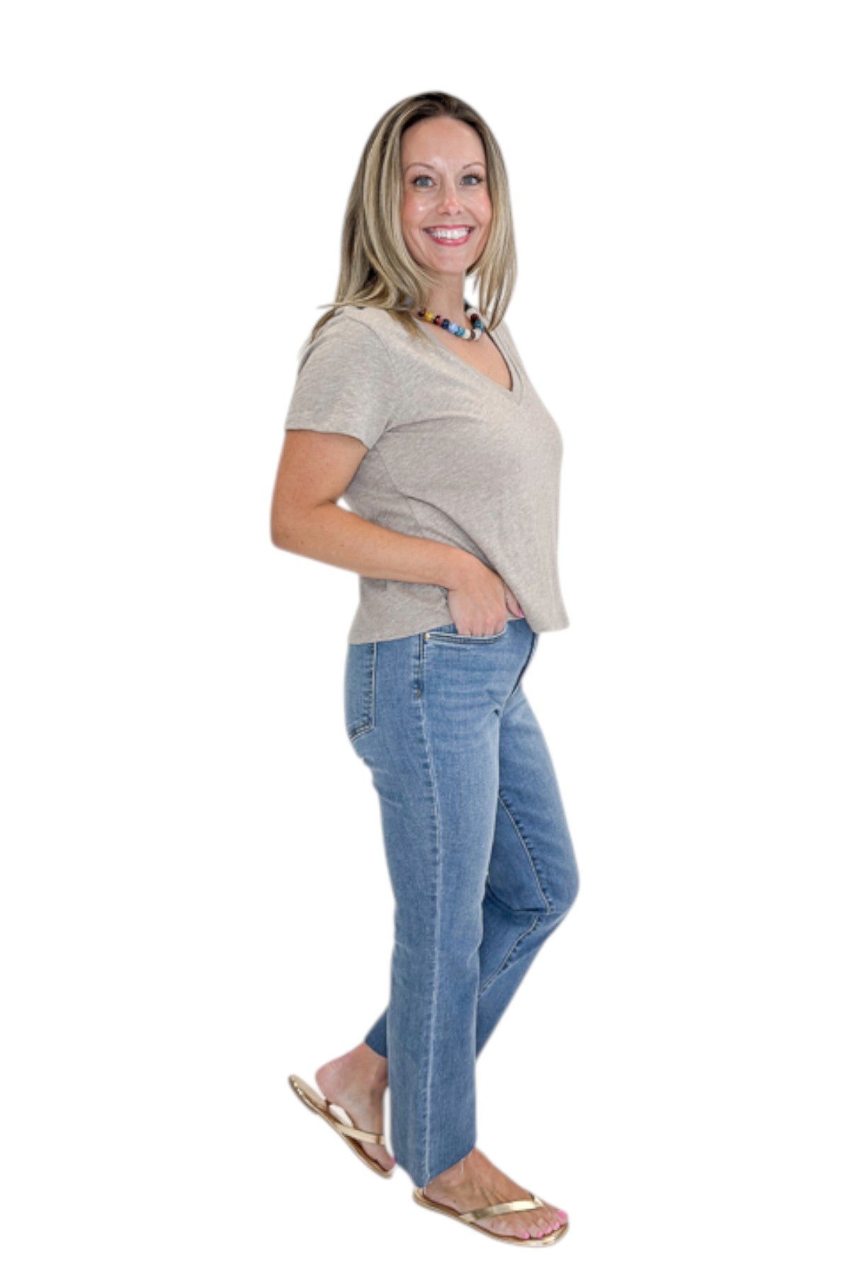 Side view of woman wearing Swagger Boutique’s Heather Ash Nomad V-Neck Tee by Z Supply with jeans against white studio background.