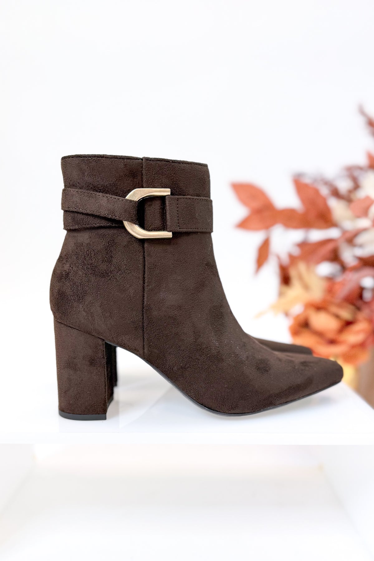 Novella- Brown Suede Buckle Booties against white studio background side view.
