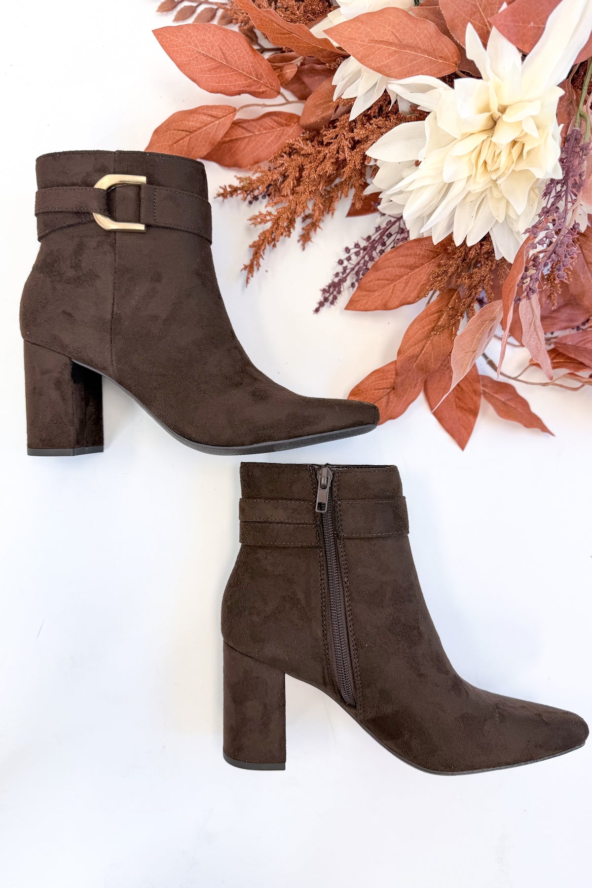 Novella- Brown Suede Buckle Booties against white studio background.