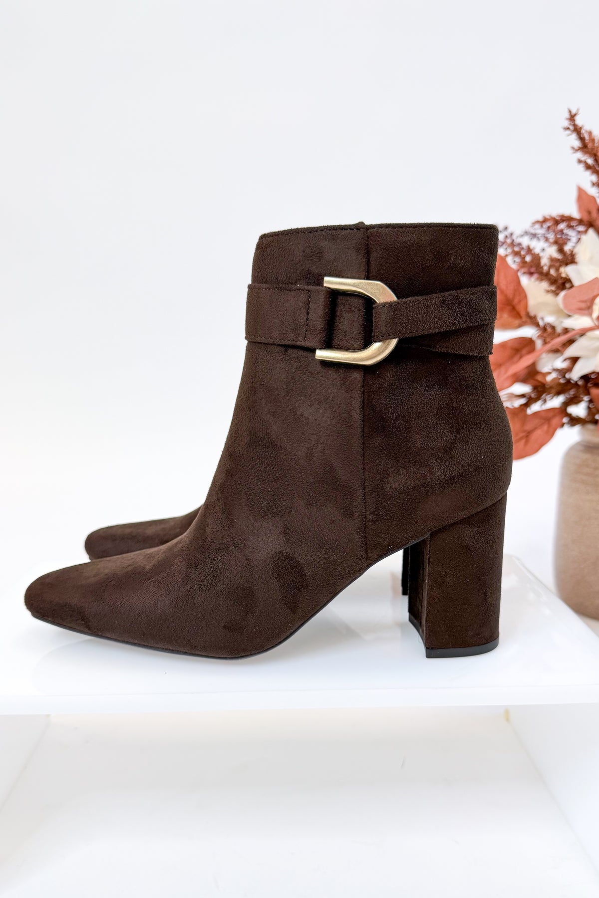 Novella- Brown Suede Buckle Booties against white studio background.
