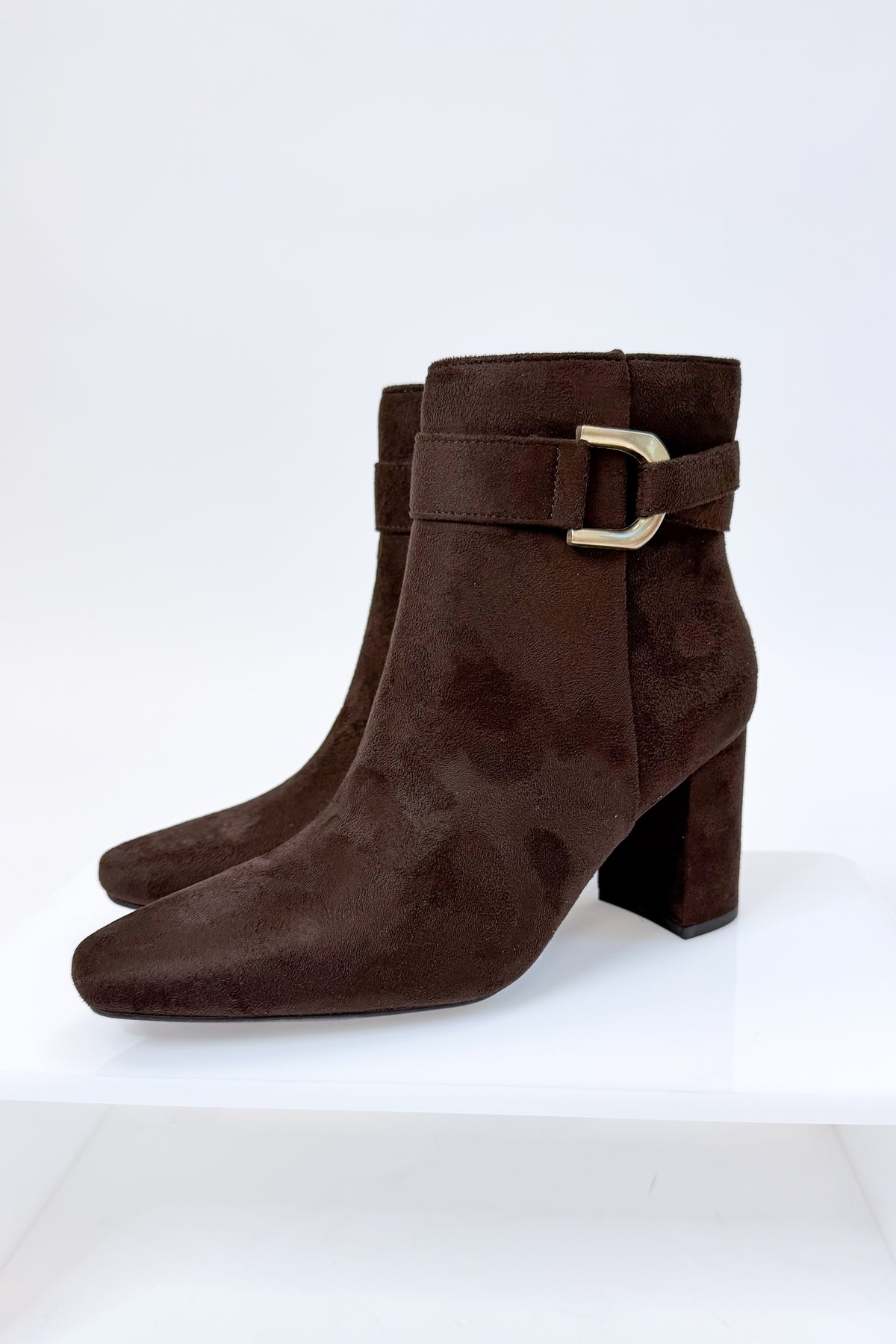 Novella- Brown Suede Buckle Booties against white studio background.