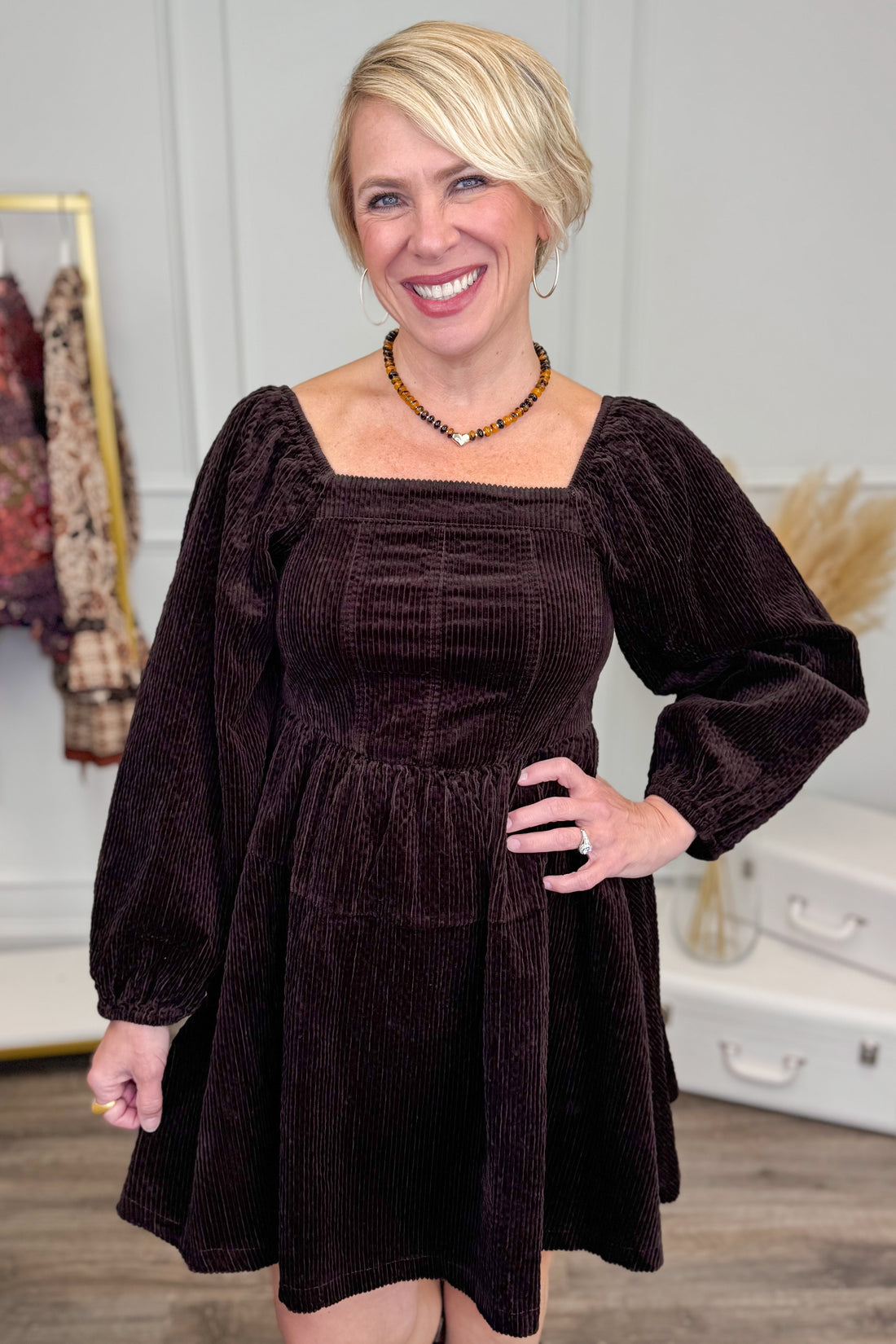 Woman wearing Brown Corduroy Puff Sleeve Dress and boots with decor in background.